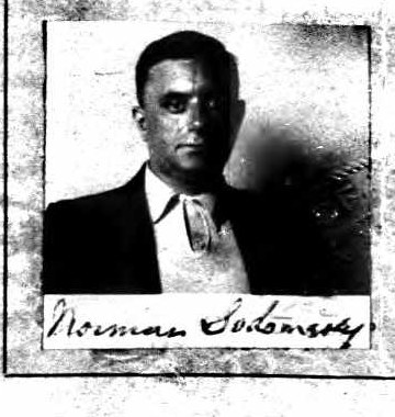 Small passport-style photograph of a man in a dark suit and tie, signed Norman Sodomsky